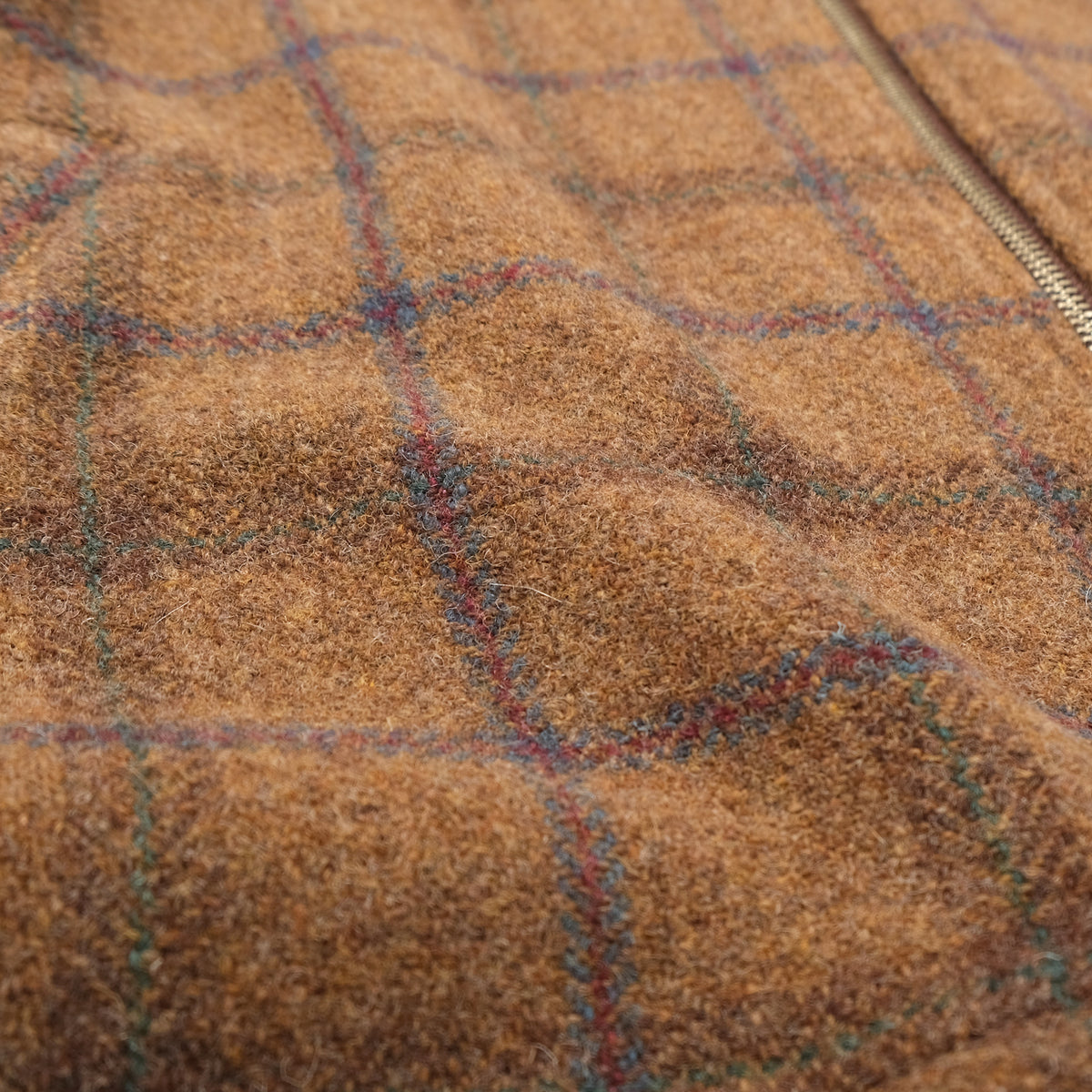 Brown wool plaid fabric close-up with blue grid pattern and textured weave