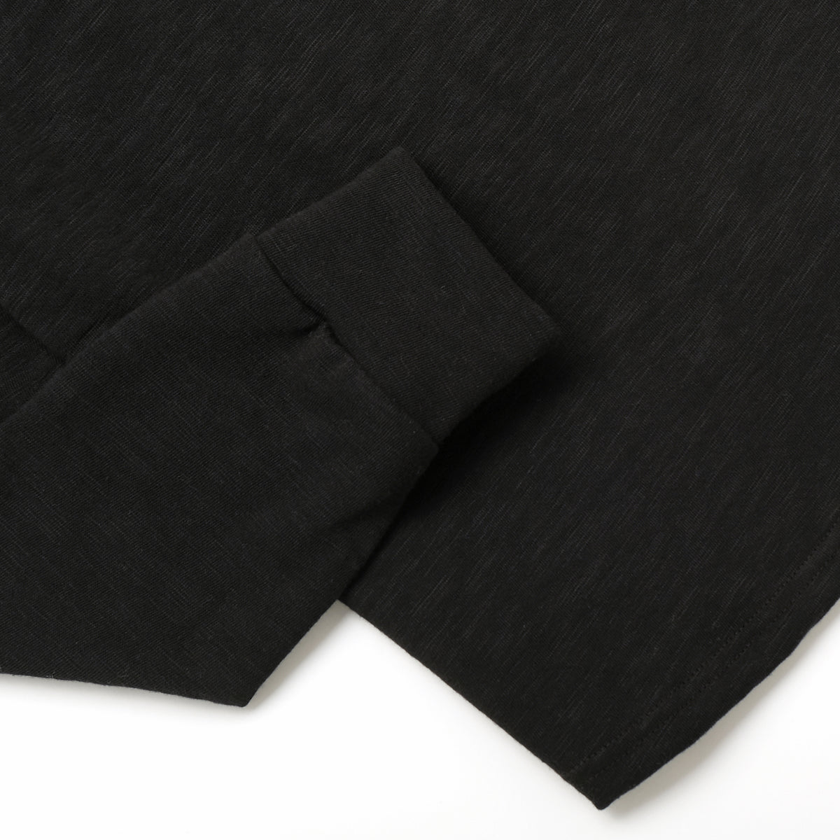 Black slub knit fabric close-up with cuff hem stitch and textured weave