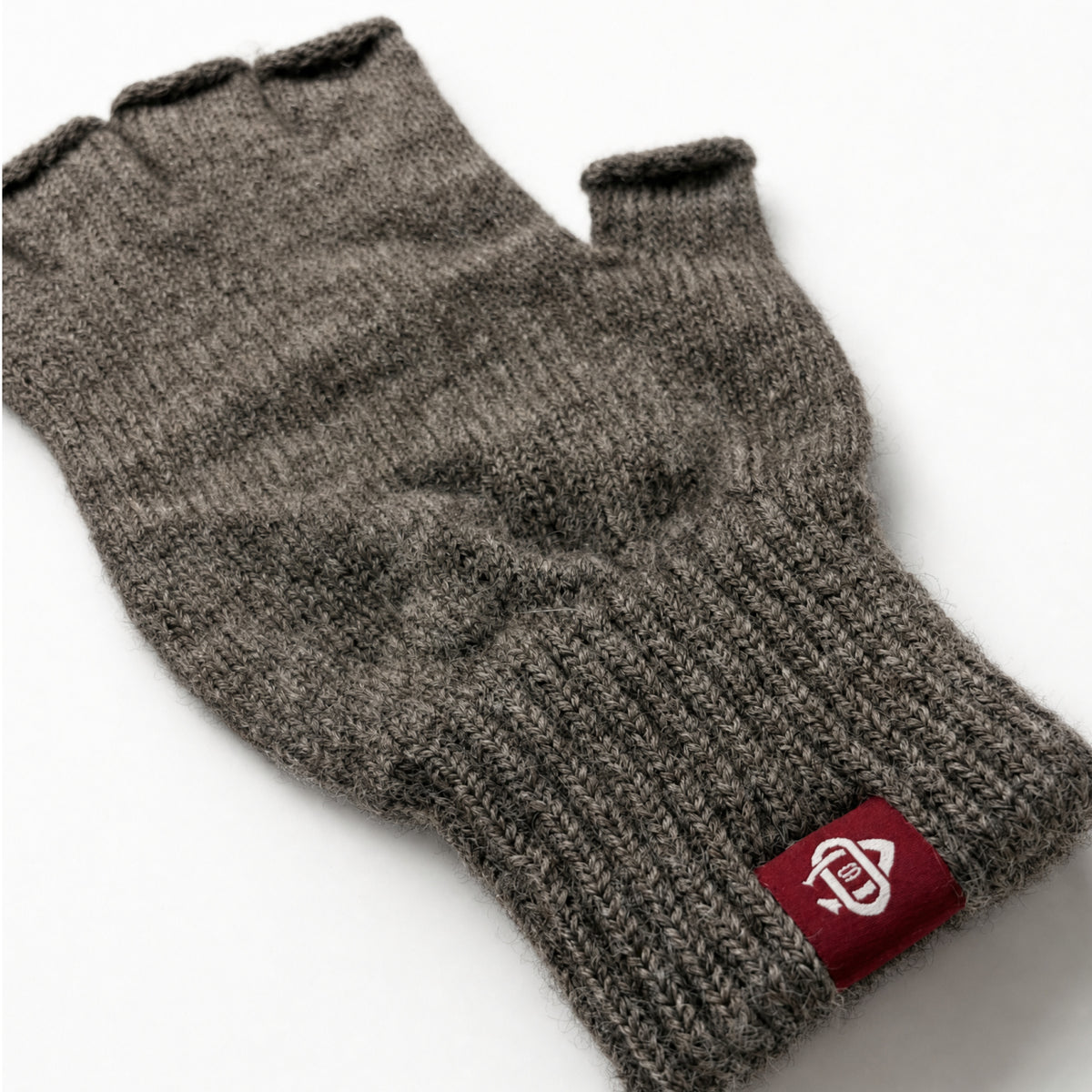 Dark gray wool fingerless glove closeup with knit texture and red logo patch