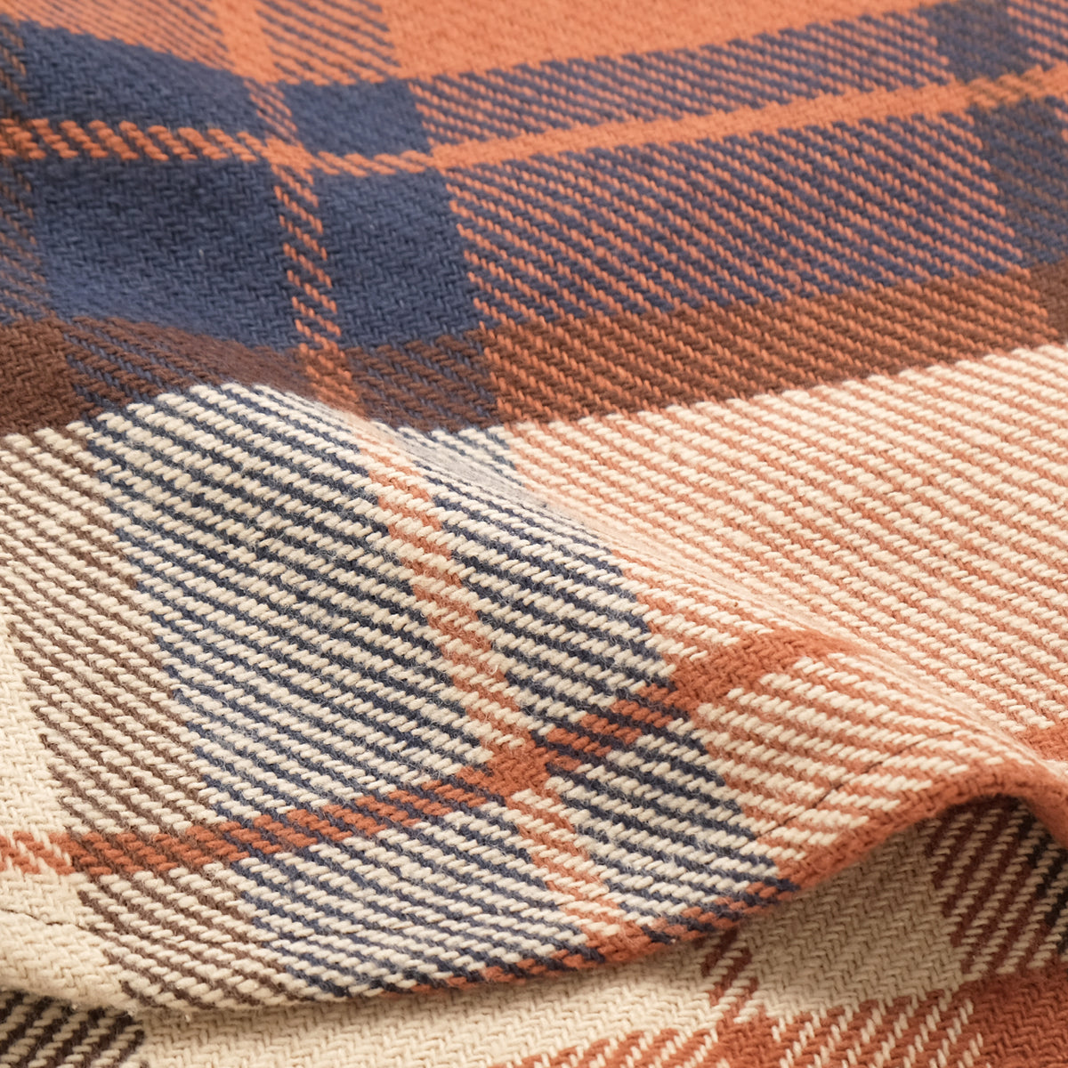 Plaid woven fabric close-up in rust, navy, and cream with textured weave