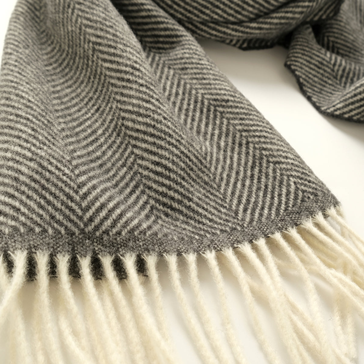 Charcoal herringbone scarf detail with textured weave and white fringe