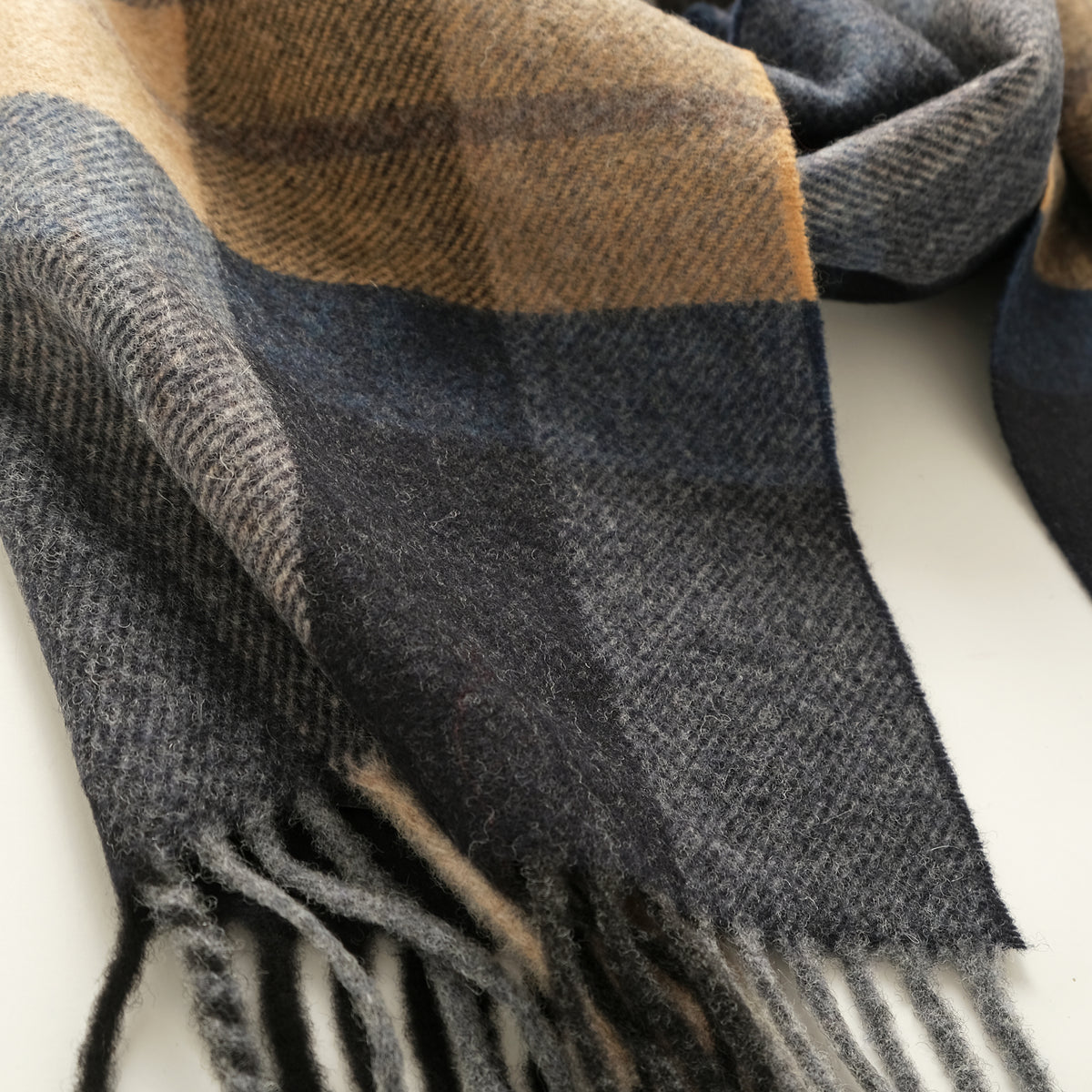 Close-up of plaid scarf fabric in gray and navy with fringed edge