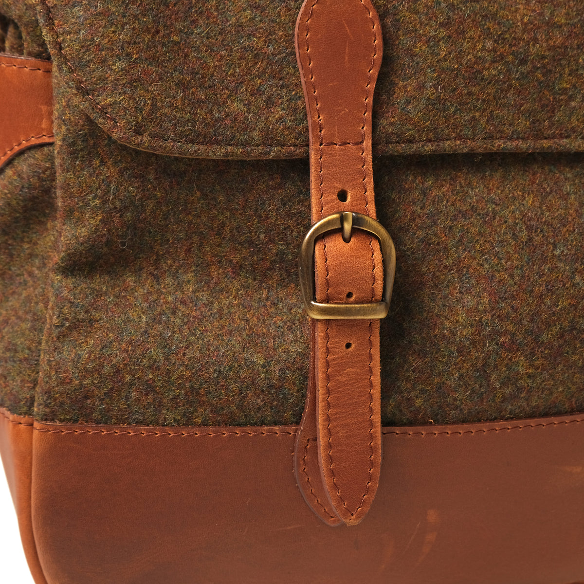 Front leather strap buckle on wool messenger bag with stitched edges
