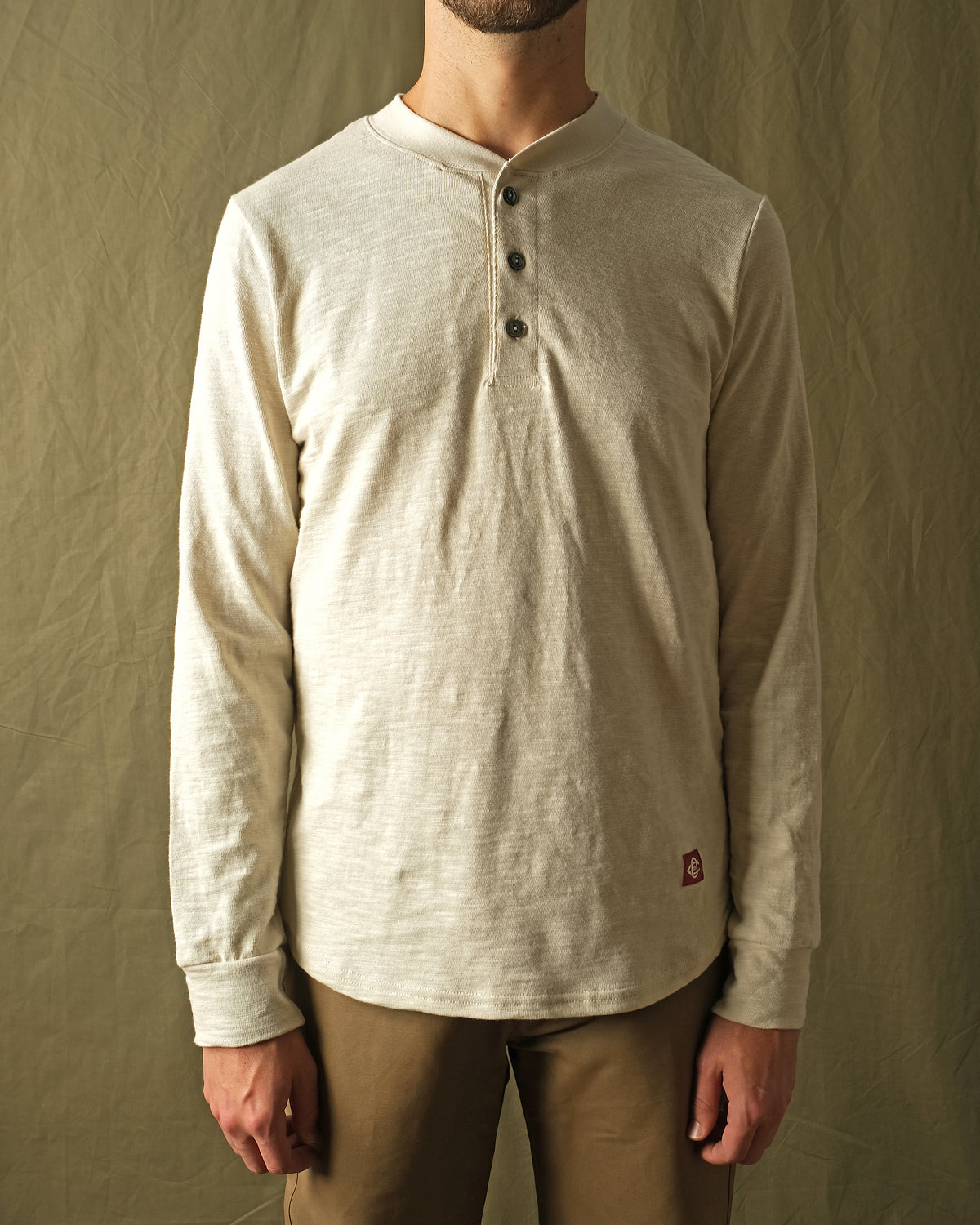 Ecru long-sleeve henley shirt on male model, three-button front