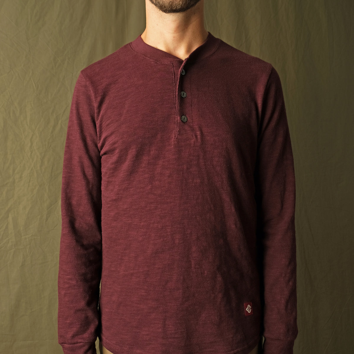 Maroon long-sleeve henley shirt on model, textured knit and button placket