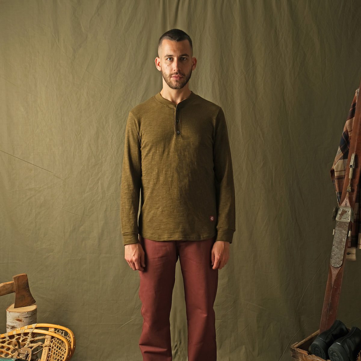 Olive long-sleeve henley shirt worn by model, 3-button placket and ribbed cuffs
