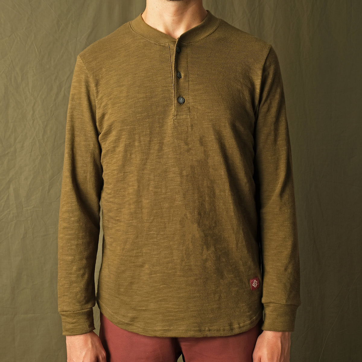 Olive long-sleeve henley shirt on model, button placket at center front
