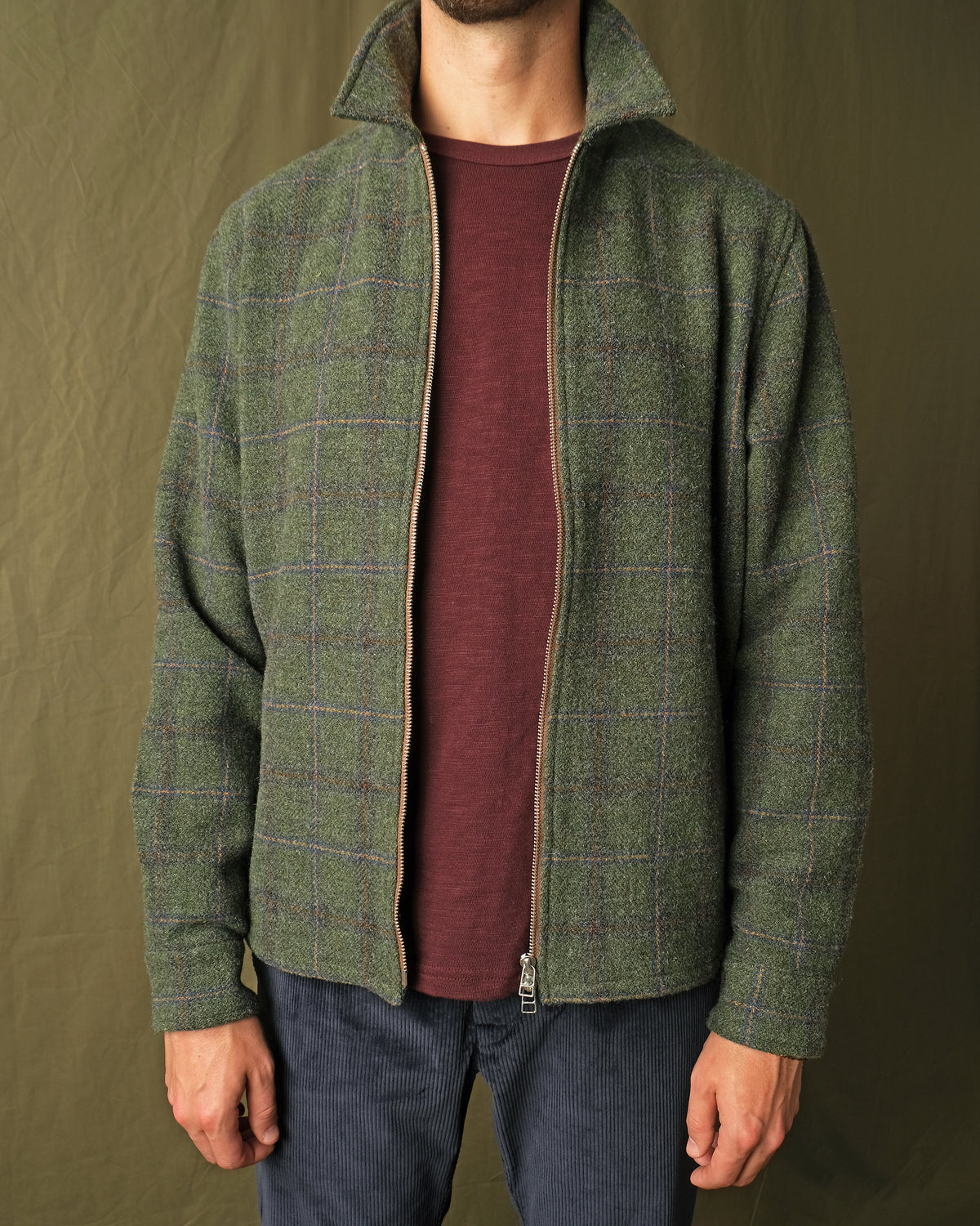 Olive green plaid wool zip overshirt on model, stand collar and visible zipper
