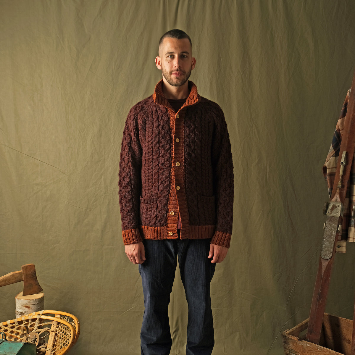 Men's dark maroon cable-knit mock neck cardigan with orange front placket and pockets