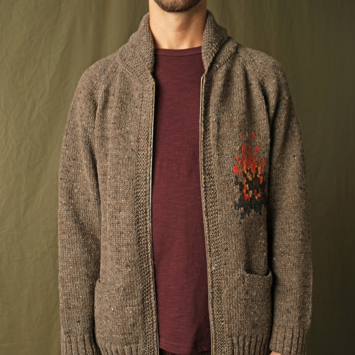 Brown full-zip cardigan worn by a man, showing left-chest campfire embroidery