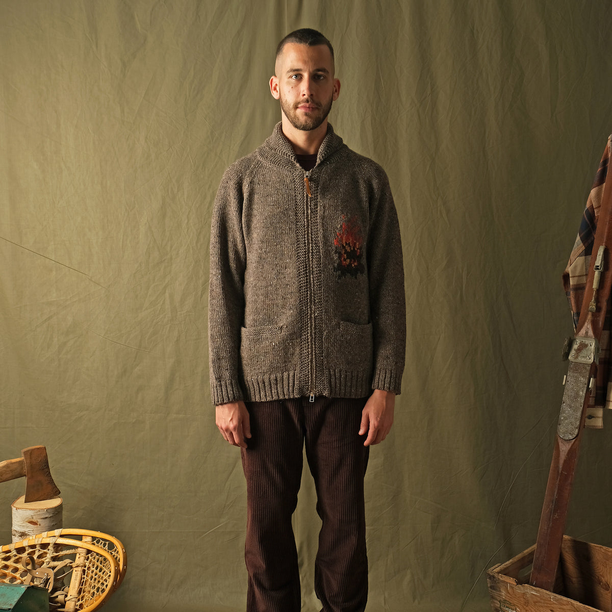 Gray knit zip cardigan with campfire motif on chest, ribbed cuffs and hem.