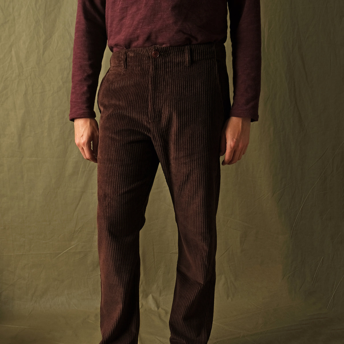 Dark brown corduroy camp pants with wide leg and cuffed hem on model.