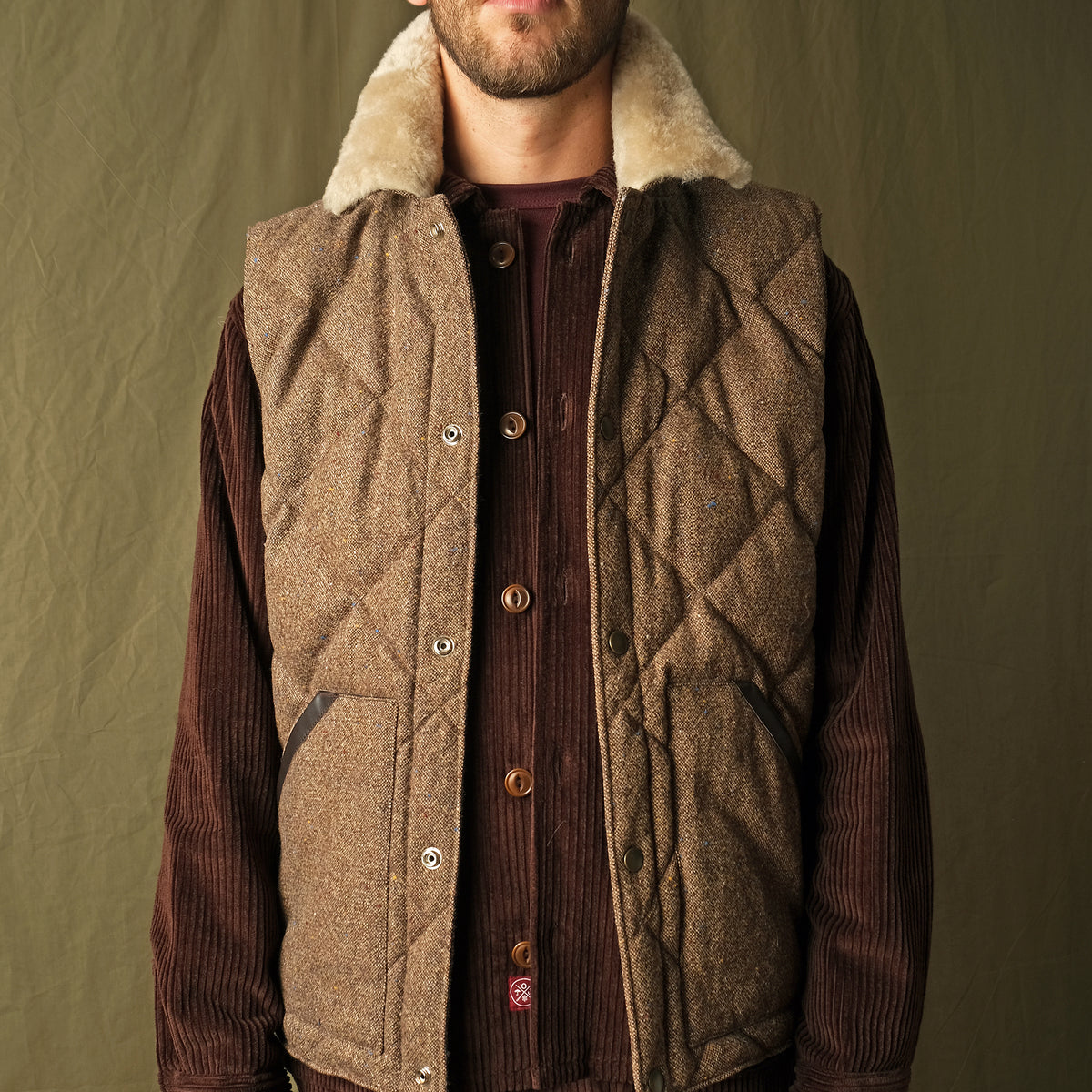 Brown quilted down vest with tan sherpa collar and button front with chest pockets