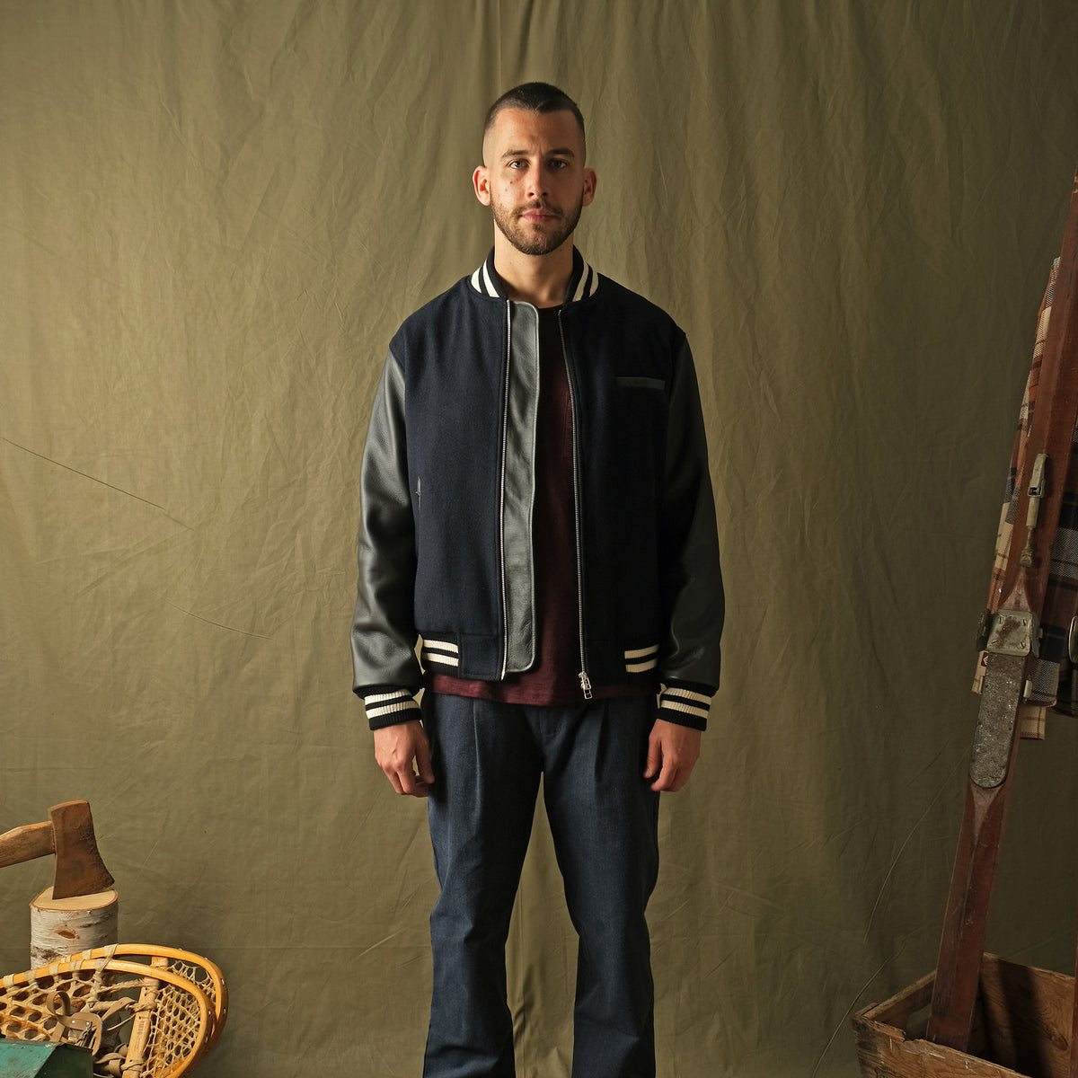 Navy bomber jacket worn with dark pants; ribbed cuffs and hem with striped trim