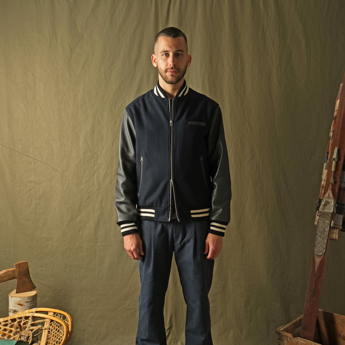 Navy bomber jacket with striped ribbed collar, cuffs, and zipper front on model