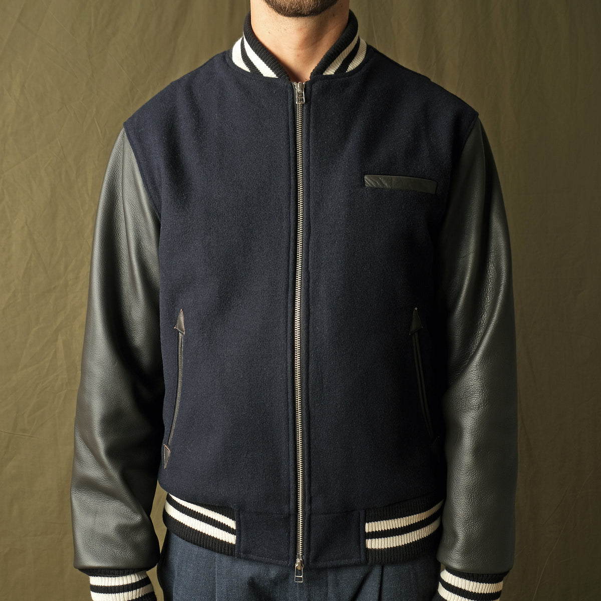 Navy bomber jacket with striped ribbed collar and cuffs; front zipper and chest pocket