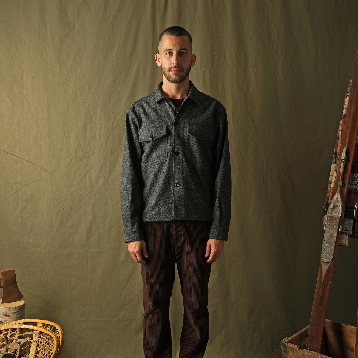 Dark charcoal speckled wool camp shirt on model, long sleeves and flap chest pockets.