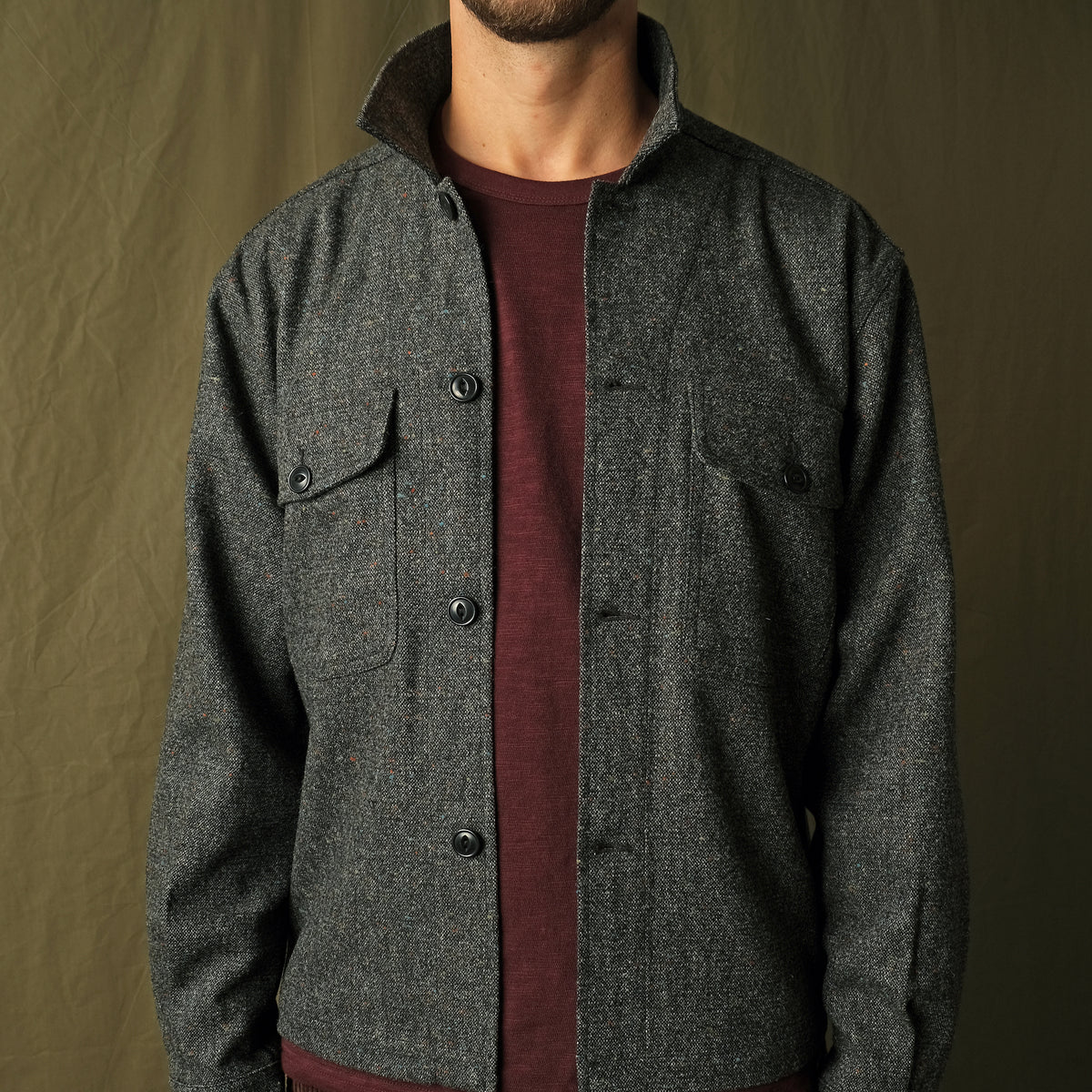 Charcoal fleck wool camp shirt with camp collar and two flap chest pockets, buttoned.