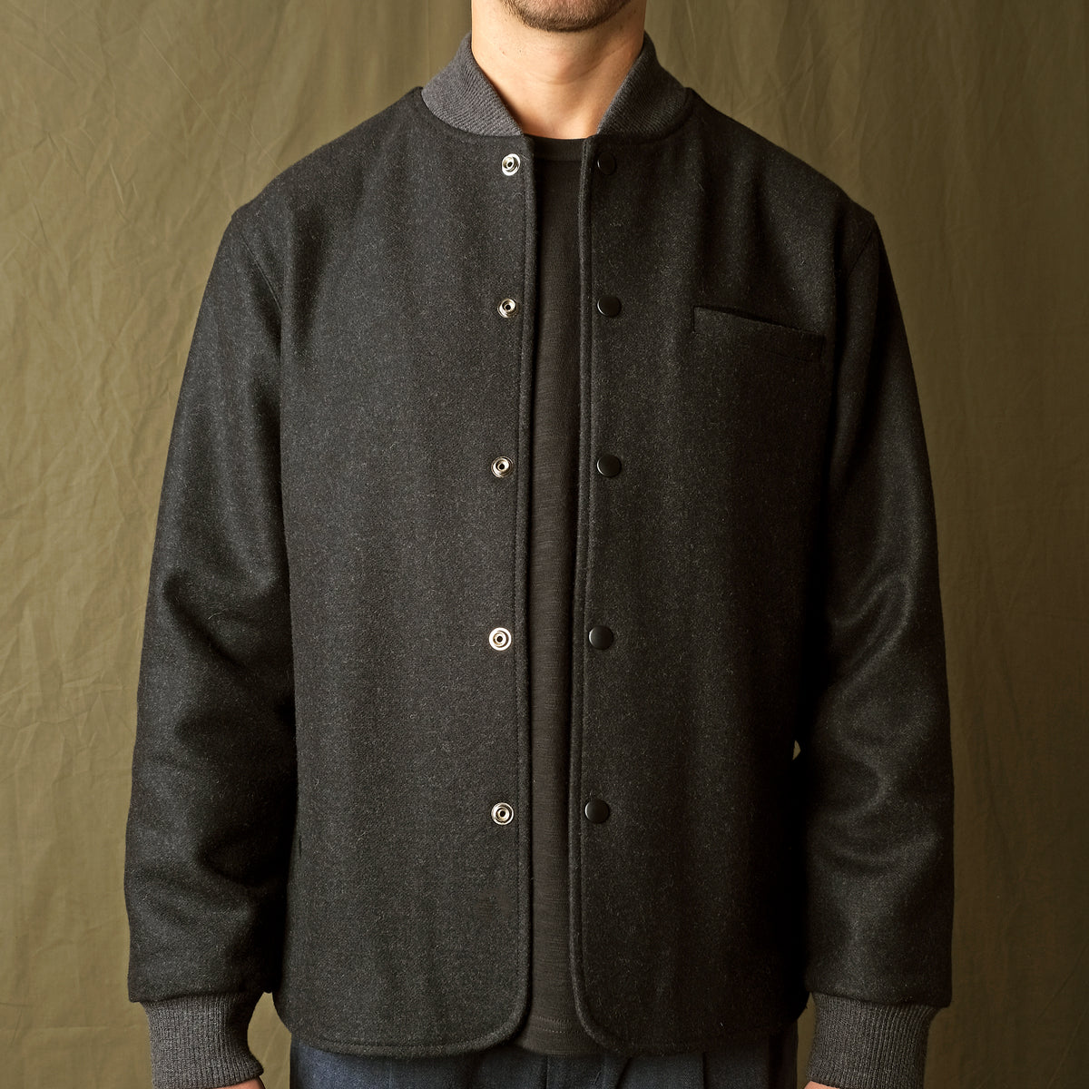 Charcoal stadium jacket front close-up with snap placket and ribbed cuffs