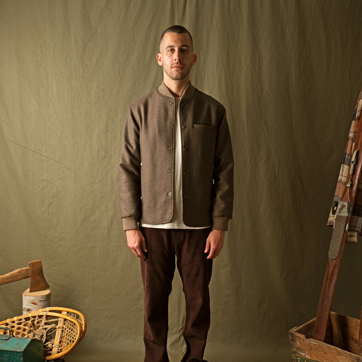 Mens brown stadium jacket with snap button front, stand collar, and chest pocket