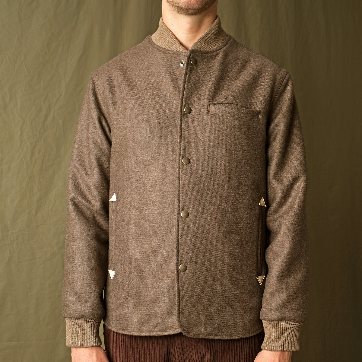 Brown stadium jacket with snap button front, stand collar, chest pocket, ribbed cuffs