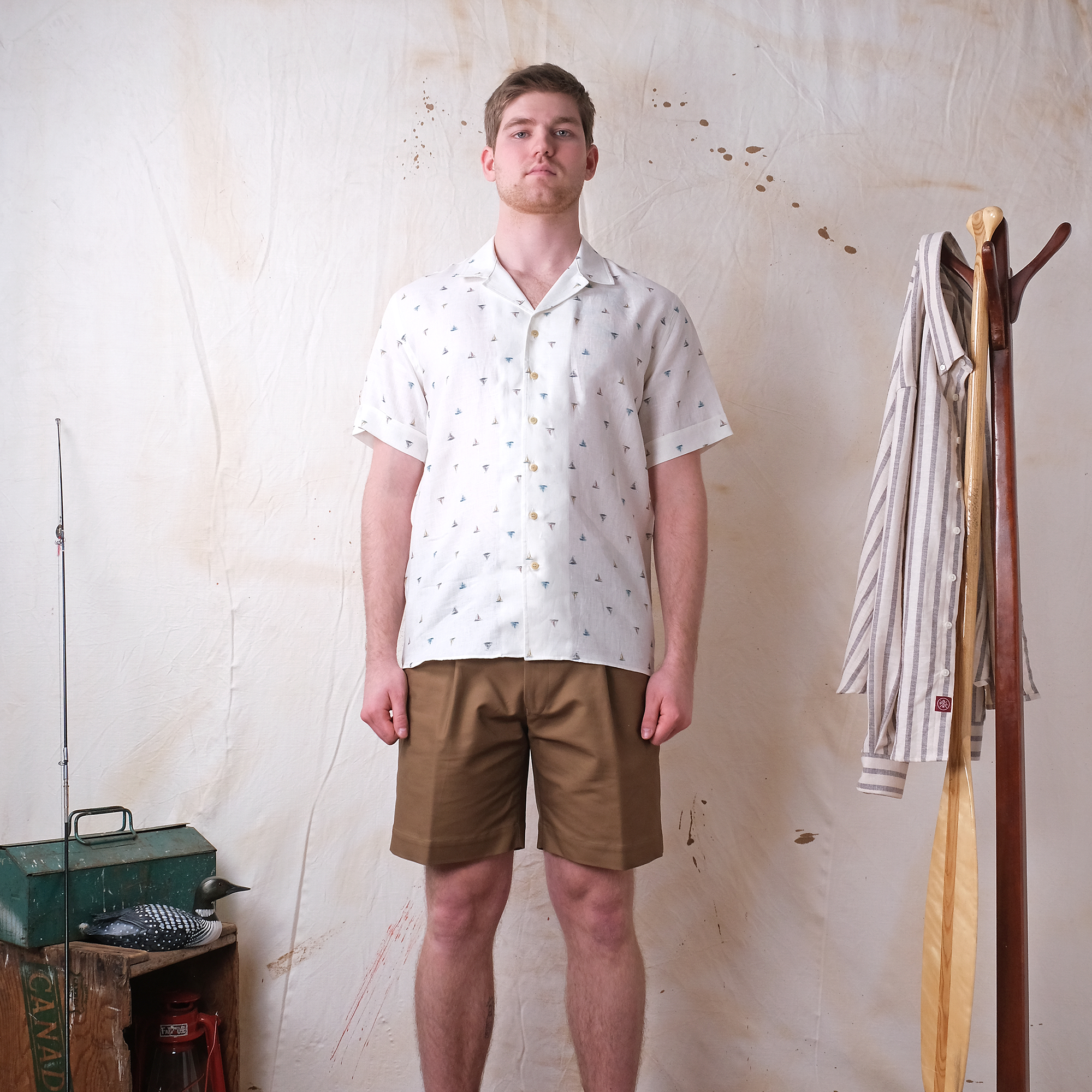 White short-sleeve button-up sailboat print shirt worn with tan shorts