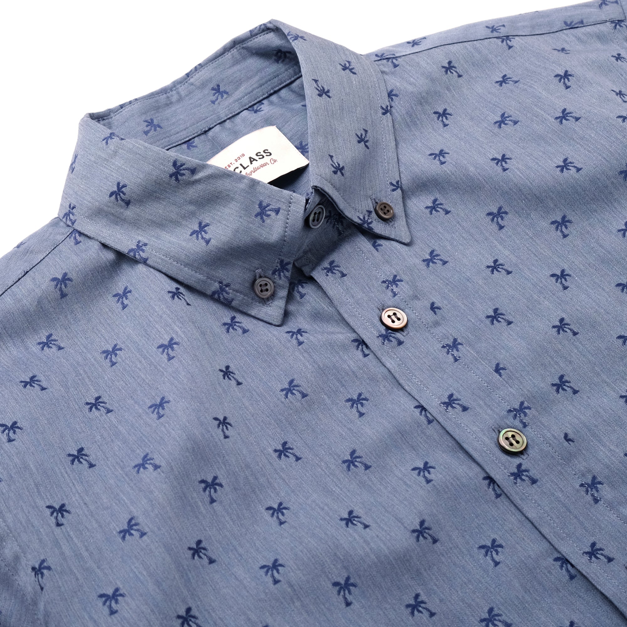 Light blue button-up shirt with navy palm print, curved open collar detail