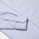Blue dress shirt chest detail with spread collar and white button close-up