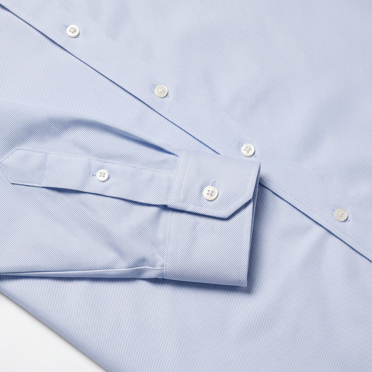 Blue dress shirt chest detail with spread collar and white button close-up