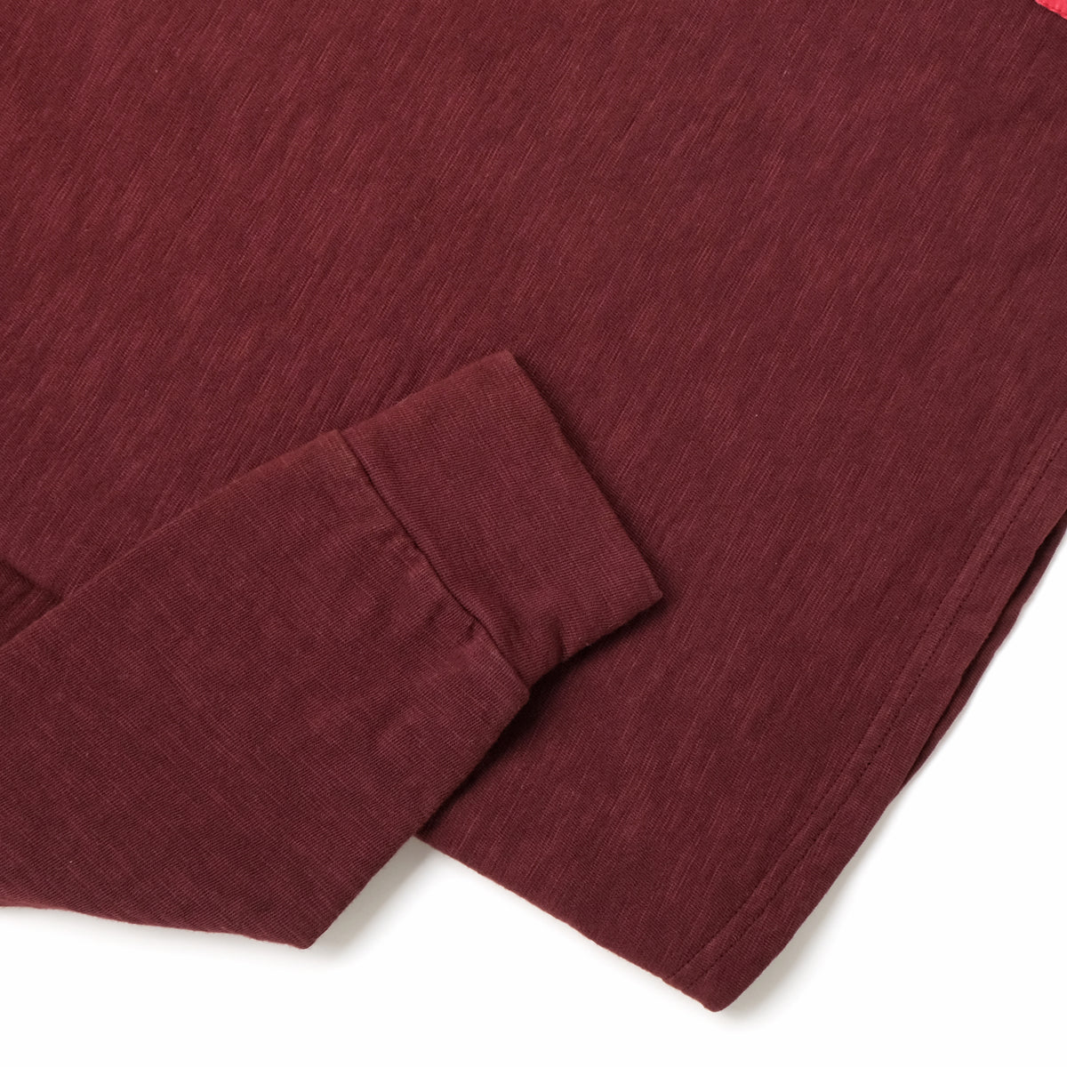 Maroon long-sleeve henley top with ribbed cuffs and button placket