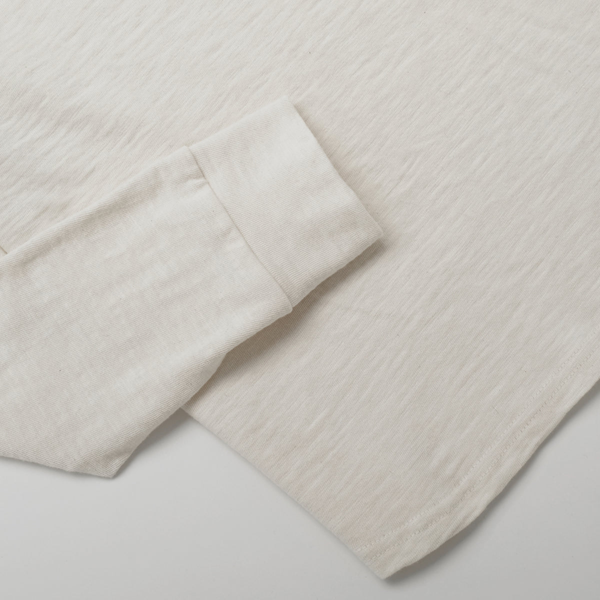 Ecru long-sleeve henley shirt sleeve and curved hem detail
