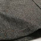 Charcoal fleck wool fabric close-up with multicolor speckled texture.