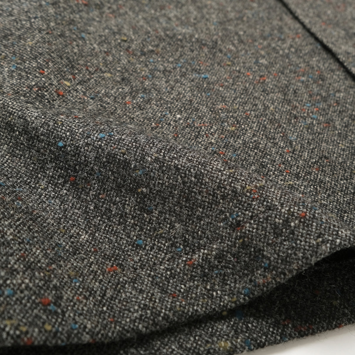 Charcoal fleck wool fabric close-up with multicolor speckled texture.