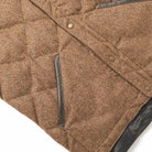 Quilted brown down vest close-up with diagonal chest pocket and metal buttons
