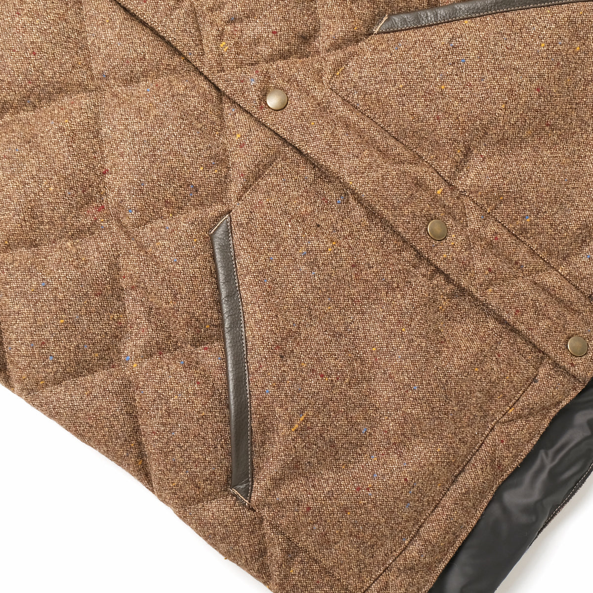 Quilted brown down vest close-up with diagonal chest pocket and metal buttons