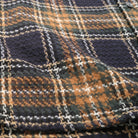 Tartan plaid fabric swatch with woven checks, navy base with tan and orange threads