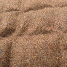 Brown diamond-quilted fabric texture close-up with small multicolor flecks