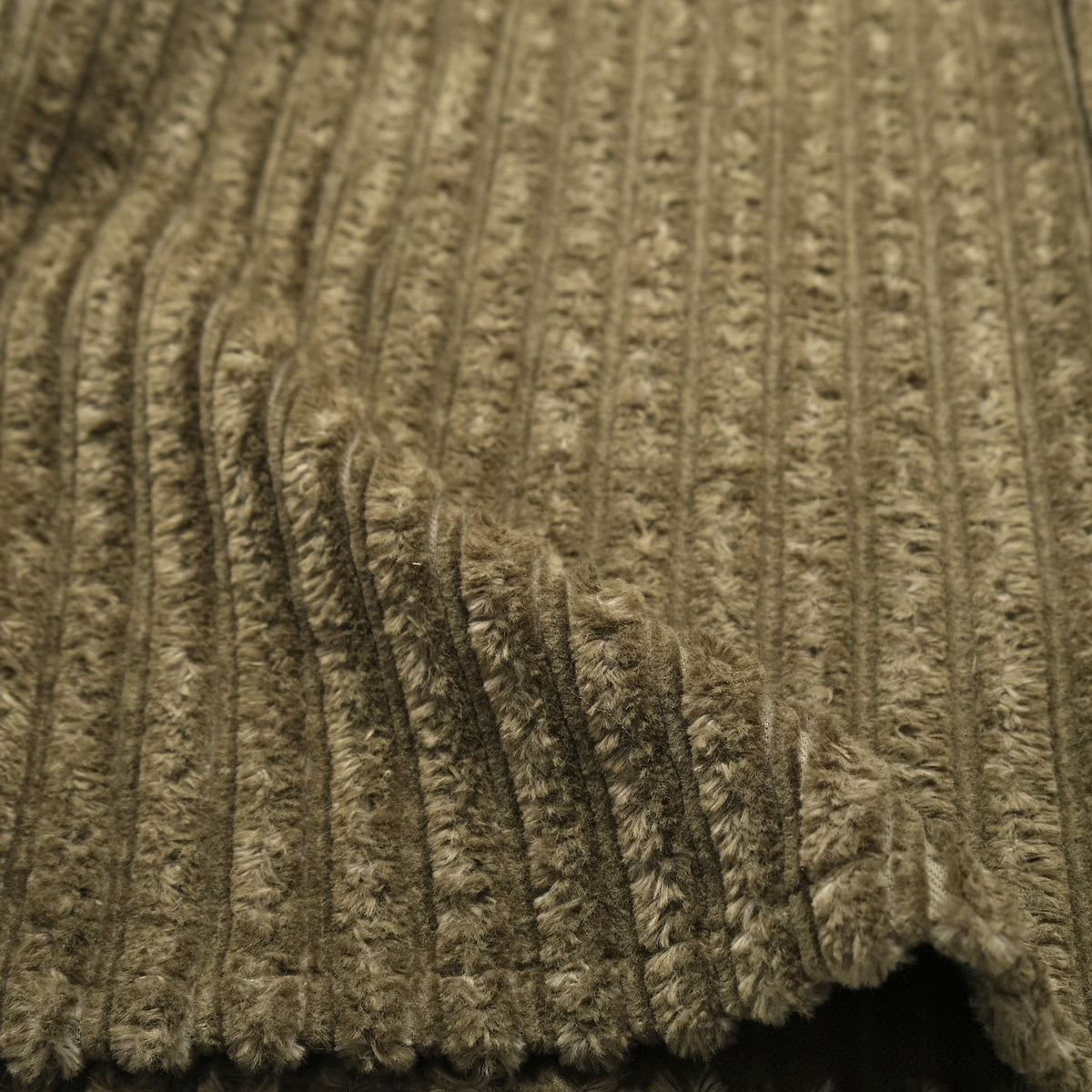 Olive jumbo corduroy fabric close-up with raised vertical ridges and soft texture