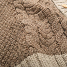 Close-up of taupe cable knit texture with contrasting cream ribbed trim