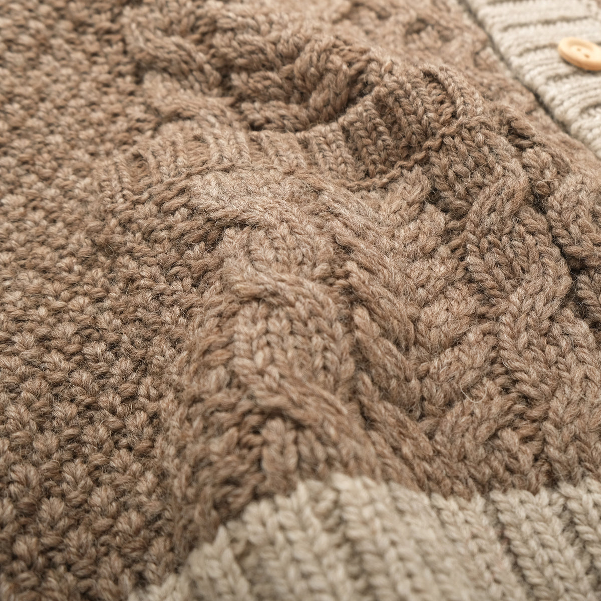 Close-up of taupe cable knit texture with contrasting cream ribbed trim
