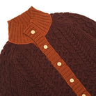 Dark maroon cable-knit cardigan close-up with orange mock neck and button placket