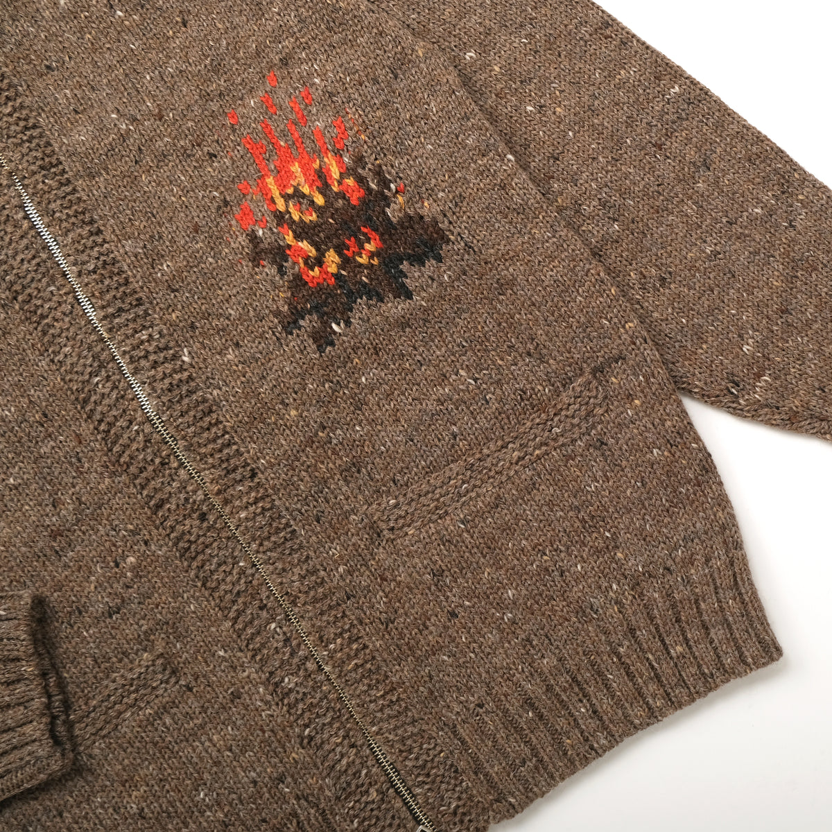 Brown knit sleeve detail with campfire motif and silver zipper along the front