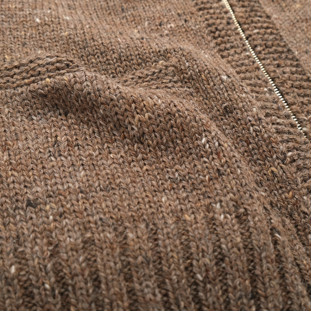 Brown textured knit fabric close-up with ribbed sleeve cuff