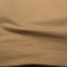 Tan moleskin engineer pants fabric close-up with visible stitching along the hem