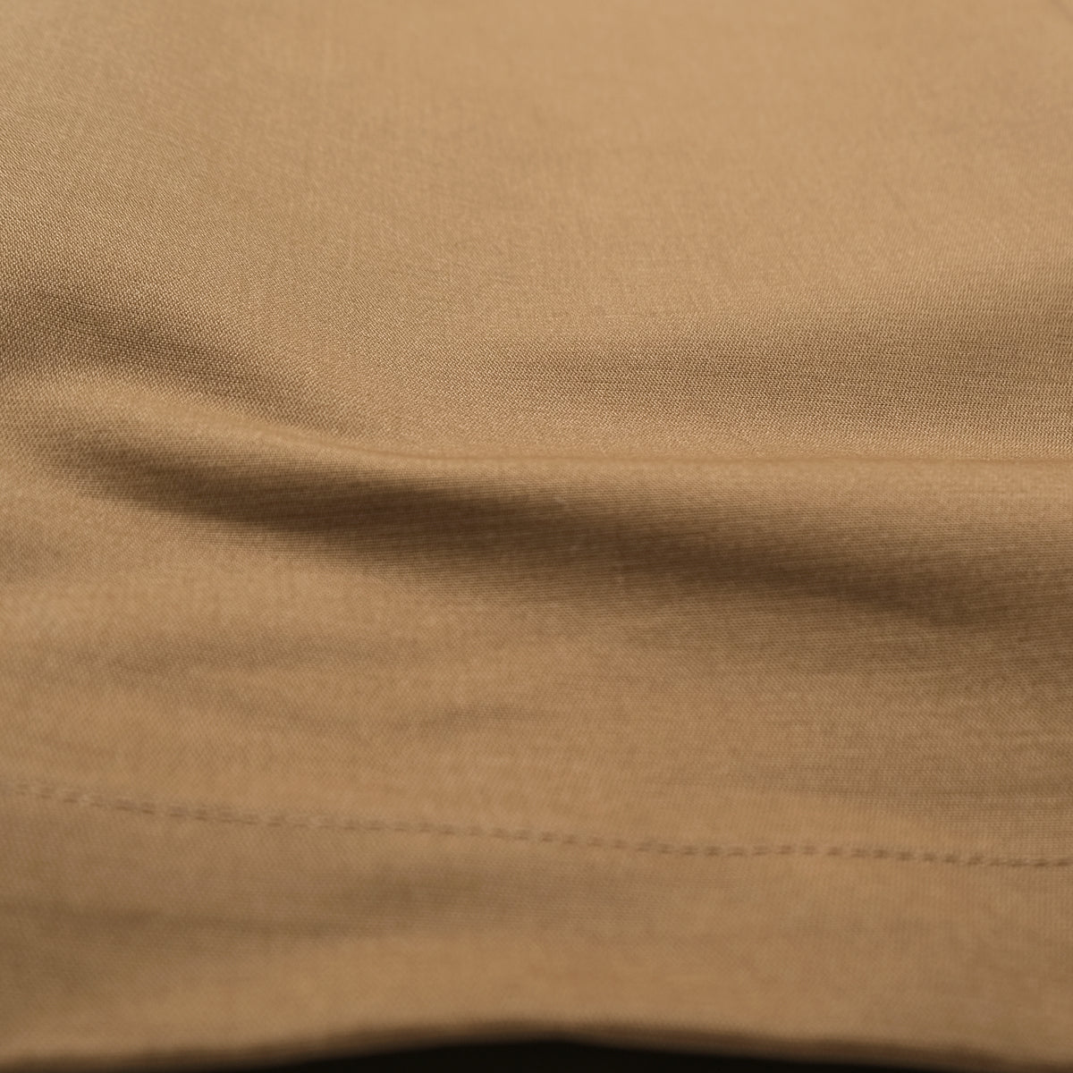 Tan moleskin engineer pants fabric close-up with visible stitching along the hem