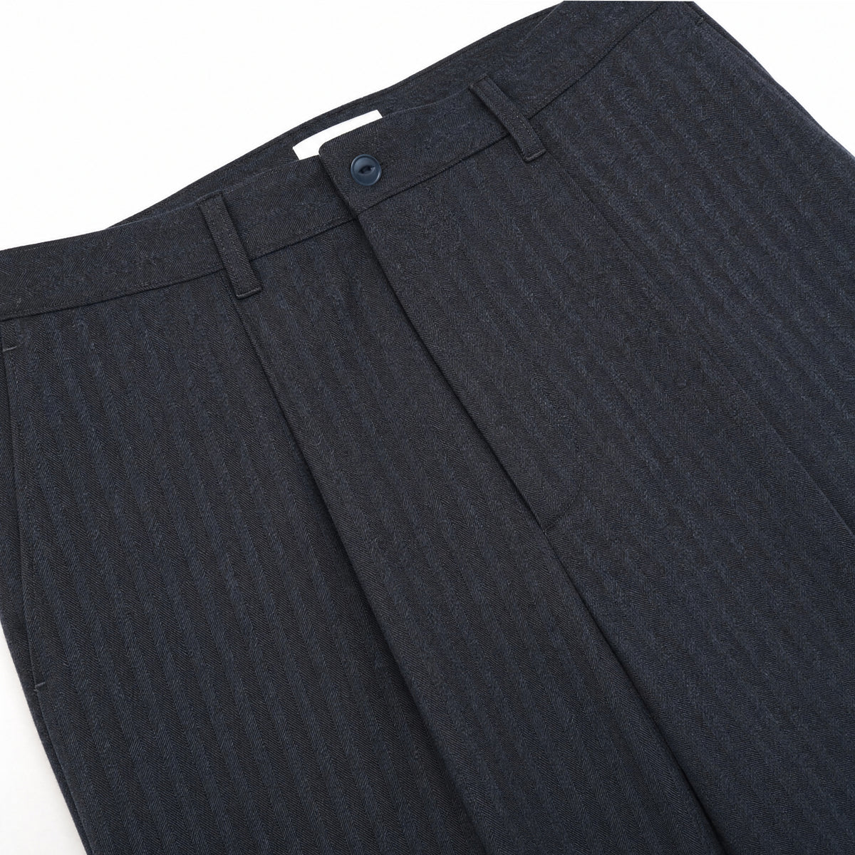 Navy herringbone pleated pants close-up of waistband and front pleats