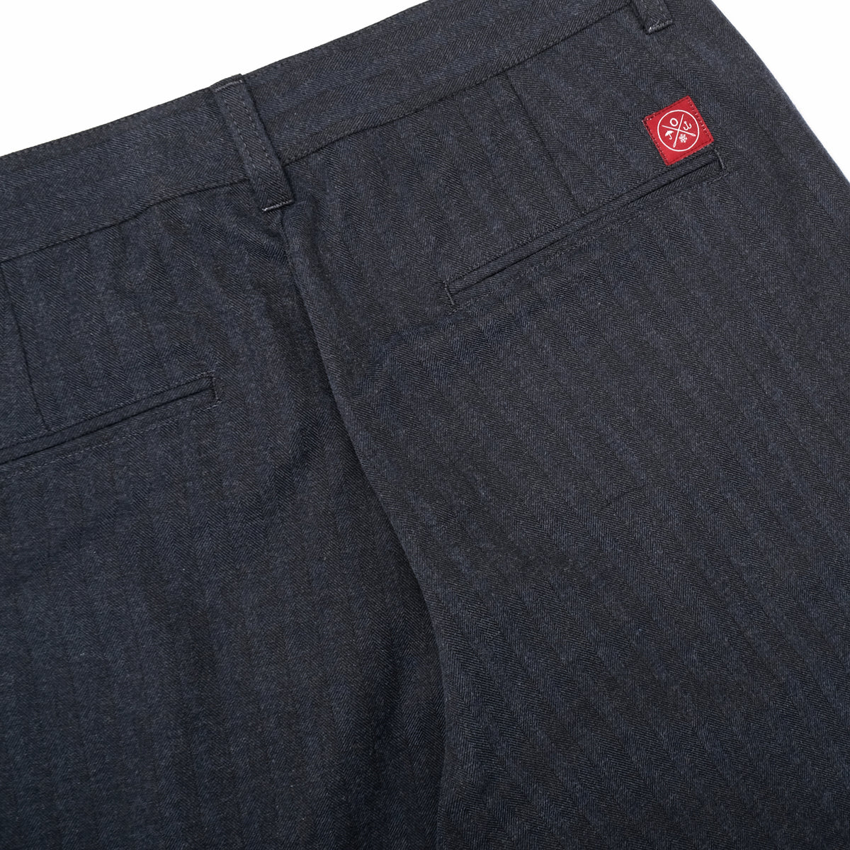 Navy pleated pants with front pockets and belt-loop waistband, logo patch at back