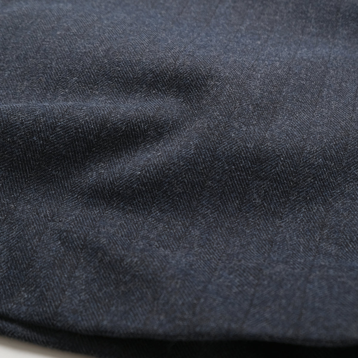 Navy herringbone fabric close-up with textured weave and subtle stripe pattern