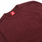 Maroon long-sleeve crewneck T-shirt with chest pocket and neck tag.