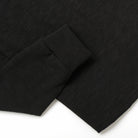 Black slub knit fabric close-up with cuff hem stitch and textured weave